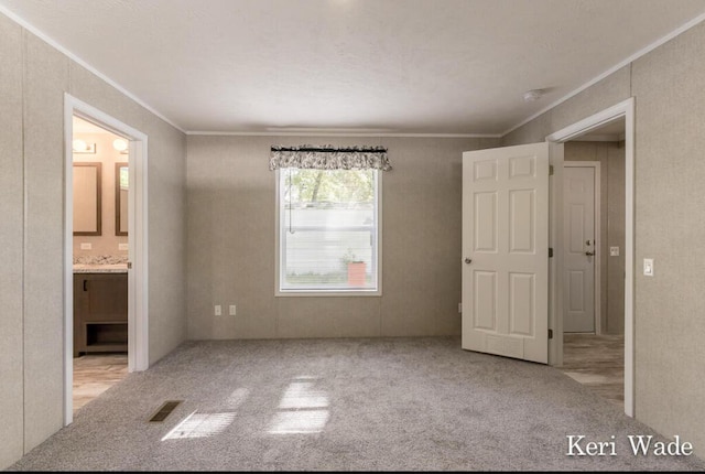 unfurnished bedroom with ensuite bathroom, ornamental molding, and light colored carpet