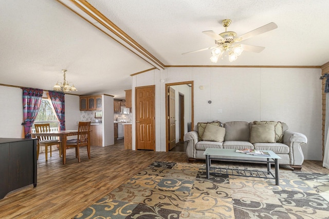 living room with dark wood-type flooring, ceiling fan with notable chandelier, vaulted ceiling with beams, ornamental molding, and a textured ceiling