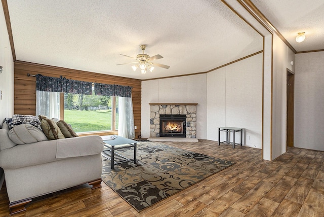 living room featuring ceiling fan, crown molding, a fireplace, dark hardwood / wood-style floors, and wood walls