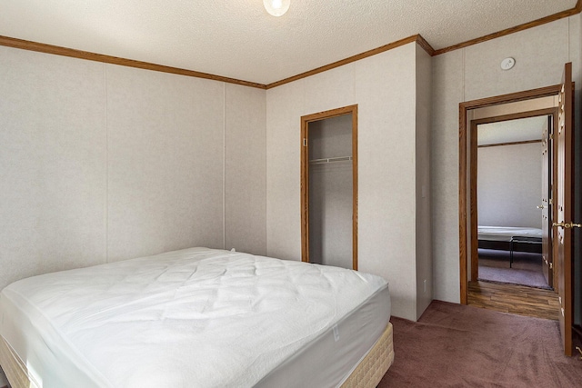 carpeted bedroom with a textured ceiling, crown molding, and a closet