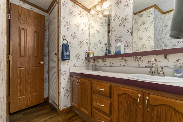 bathroom featuring hardwood / wood-style floors, vanity, an inviting chandelier, crown molding, and a textured ceiling