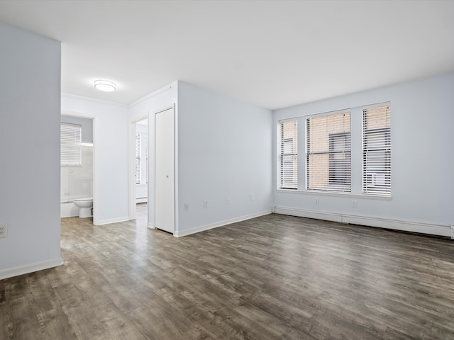 spare room with dark wood-type flooring and a baseboard radiator