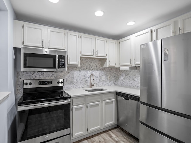 kitchen with tasteful backsplash, white cabinetry, sink, and stainless steel appliances