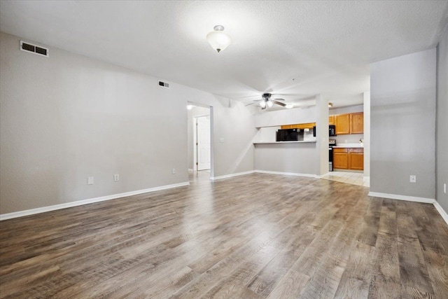 unfurnished living room featuring a textured ceiling, light hardwood / wood-style floors, and ceiling fan