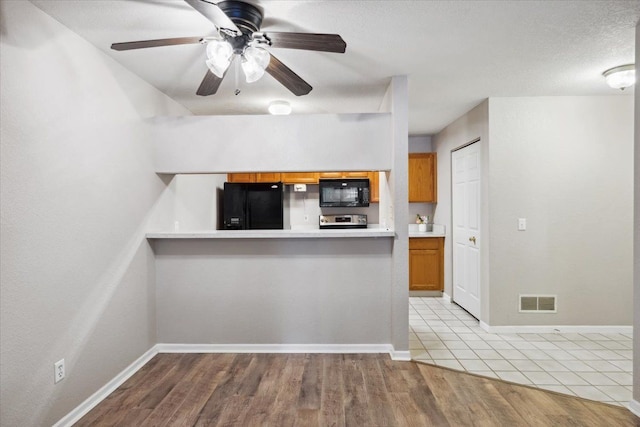 kitchen featuring a textured ceiling, light hardwood / wood-style flooring, ceiling fan, and black appliances