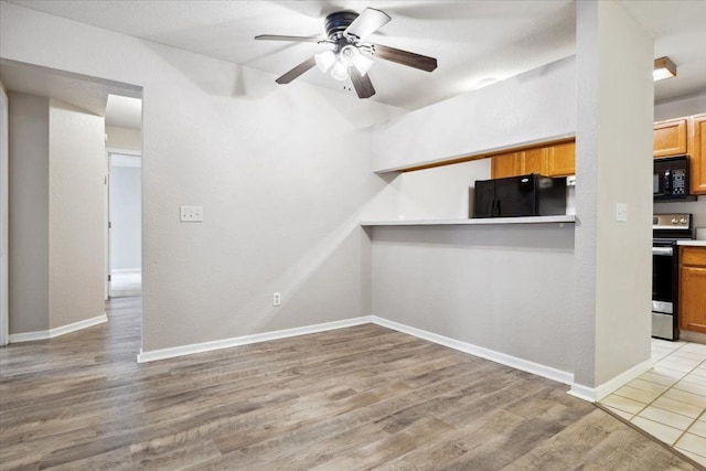 interior space with black appliances, ceiling fan, and light hardwood / wood-style flooring