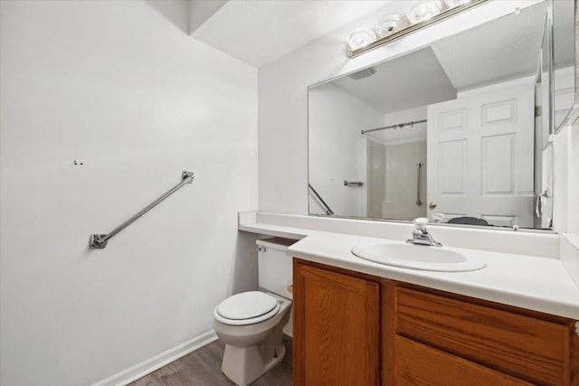 bathroom with a shower, hardwood / wood-style floors, vanity, and toilet