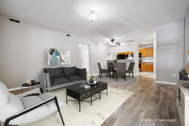 living room with ceiling fan and light hardwood / wood-style flooring