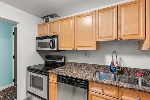 kitchen featuring tile patterned flooring, sink, stainless steel appliances, and dark stone counters