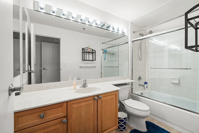 full bathroom with shower / bath combination with glass door, tile patterned floors, vanity, and toilet