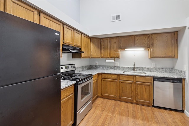 kitchen featuring sink, light stone countertops, stainless steel appliances, and light hardwood / wood-style flooring