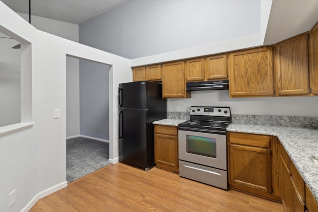 kitchen with black fridge, electric range, light stone counters, and light wood-type flooring