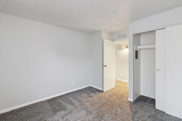 unfurnished bedroom with a closet, dark carpet, and a textured ceiling