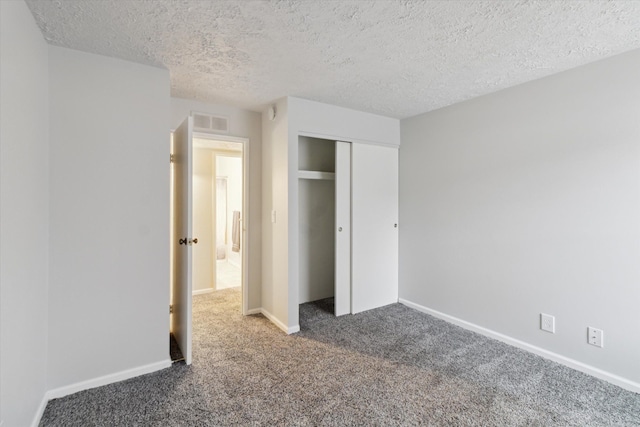 unfurnished bedroom with dark colored carpet, a textured ceiling, and a closet