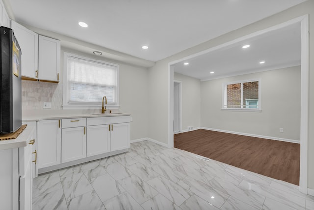 kitchen featuring white cabinets, decorative backsplash, and sink