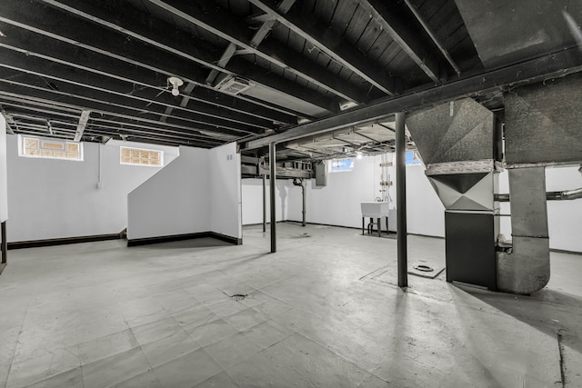 basement featuring sink, electric panel, and heating unit