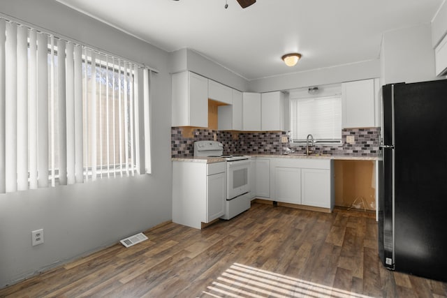 kitchen with white range with electric cooktop, decorative backsplash, black fridge, and white cabinetry