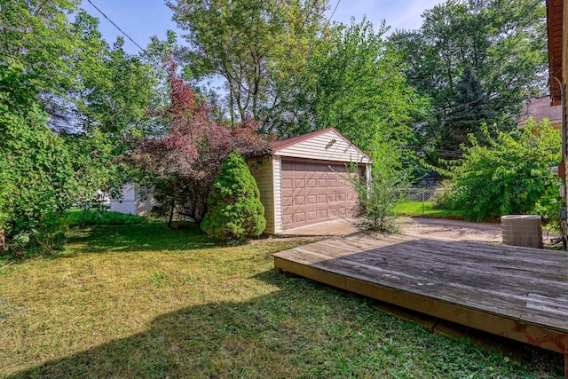 view of yard with a garage, central air condition unit, an outbuilding, and a wooden deck