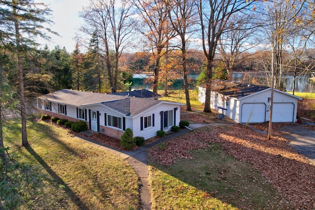 view of front facade with a water view, a detached garage, and a front yard