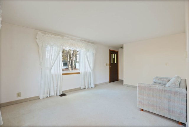 living area featuring visible vents, light carpet, and baseboards