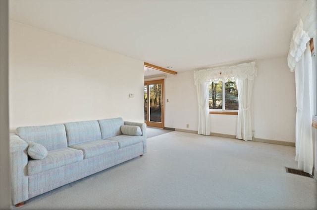 living area featuring baseboards, visible vents, and light colored carpet