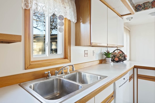 kitchen featuring a sink, dishwasher, white cabinets, and light countertops