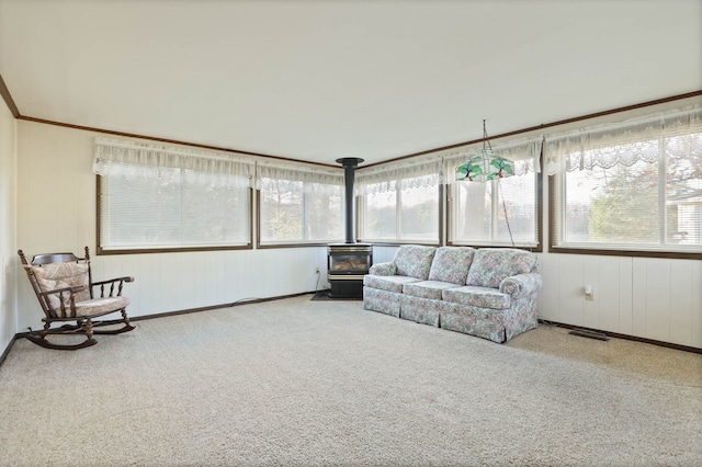 sunroom featuring a wood stove, visible vents, and plenty of natural light