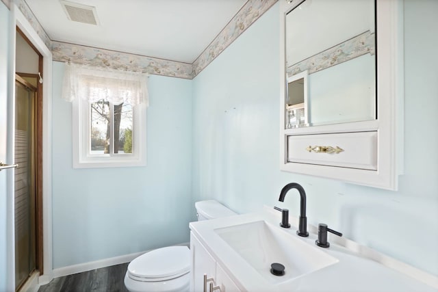 bathroom featuring baseboards, visible vents, toilet, wood finished floors, and vanity