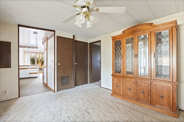 unfurnished bedroom featuring light carpet, visible vents, and a ceiling fan