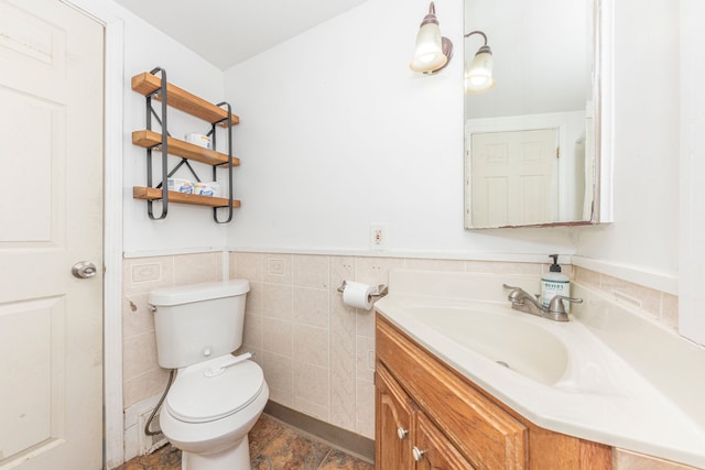 bathroom with toilet, vanity, and tile walls