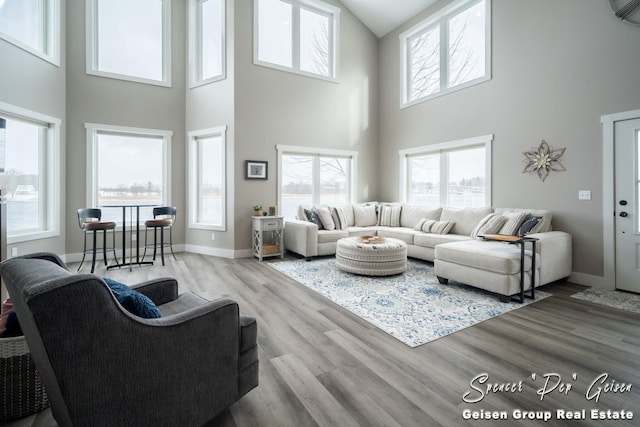 living room with a wall unit AC, wood-type flooring, and a high ceiling