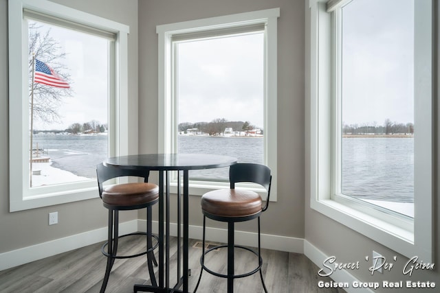 dining room with hardwood / wood-style floors and a water view