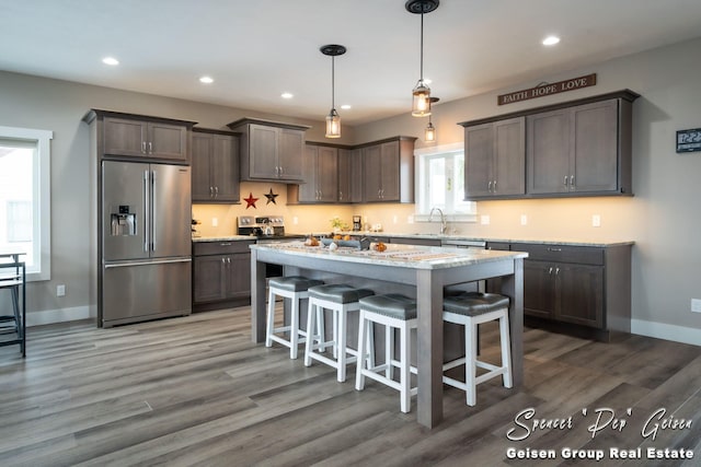 kitchen featuring appliances with stainless steel finishes, a kitchen island, hanging light fixtures, and dark wood-type flooring