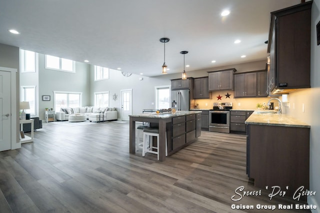 kitchen with a kitchen bar, stainless steel appliances, dark wood-type flooring, pendant lighting, and a kitchen island