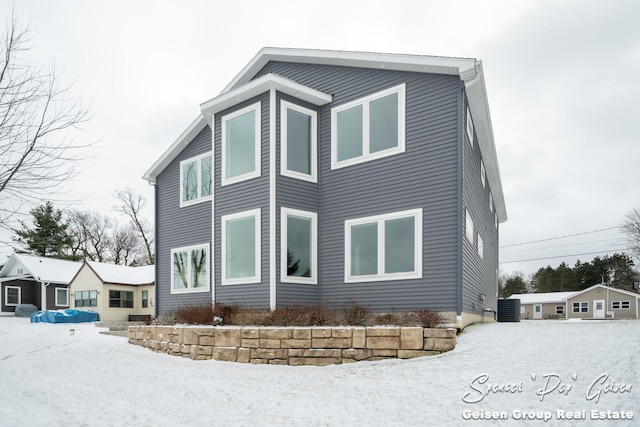 view of snow covered exterior with central AC unit