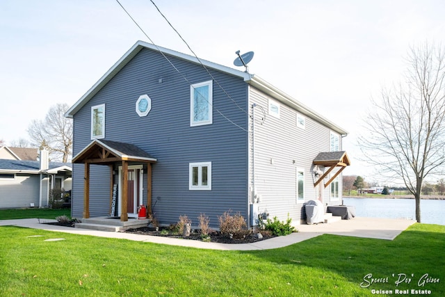 view of front of property featuring a water view, a patio area, and a front lawn