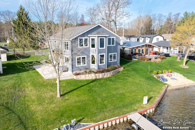 back of property with a water view and a yard