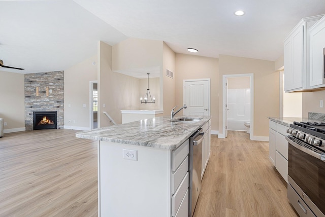 2519 Hunters Run Unit 101, Kalamazoo, MI 49048 - kitchen with sink, a stone fireplace, a kitchen island with sink, white cabinets, and appliances with stainless steel finishes