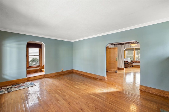 empty room with crown molding and light hardwood / wood-style flooring