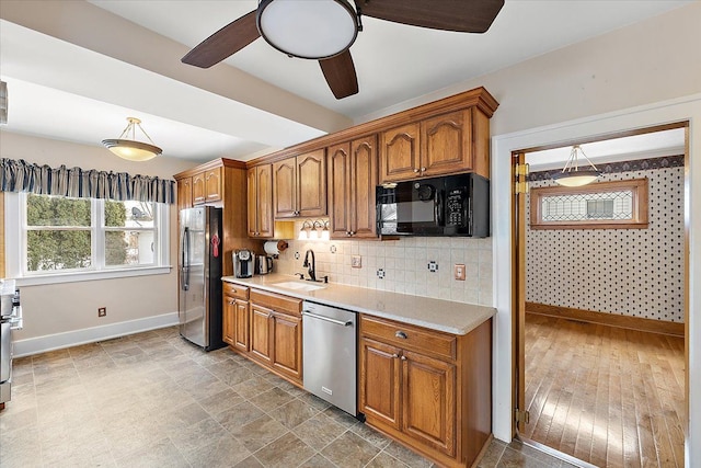 kitchen with appliances with stainless steel finishes, backsplash, ceiling fan, sink, and pendant lighting