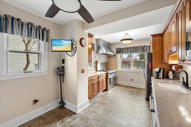 kitchen featuring backsplash, sink, stainless steel appliances, and wall chimney range hood