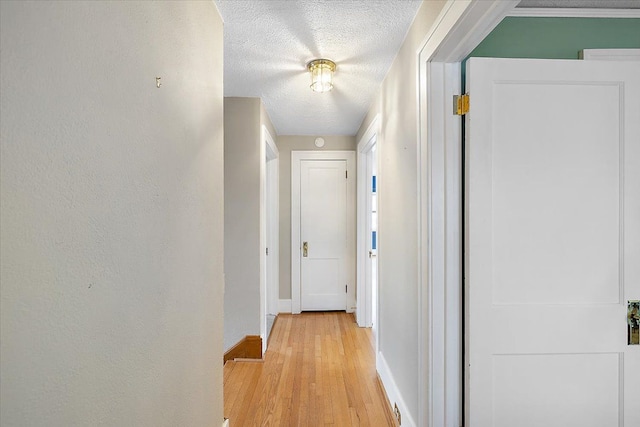 hall with a textured ceiling and light hardwood / wood-style flooring