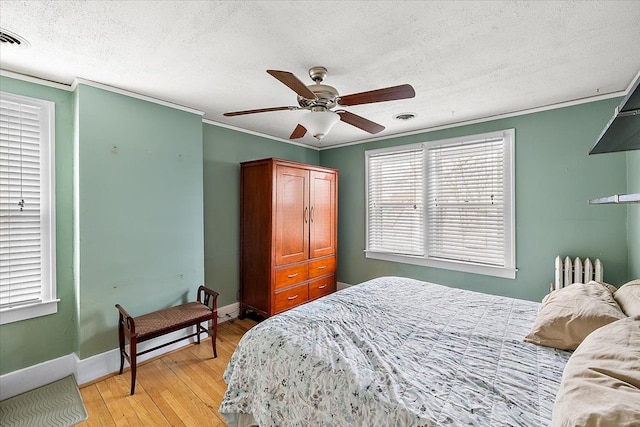 bedroom featuring radiator, crown molding, light hardwood / wood-style flooring, ceiling fan, and a textured ceiling