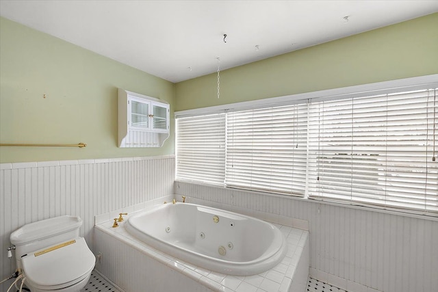 bathroom featuring tile patterned floors, tiled bath, and toilet