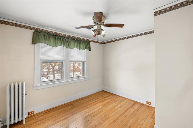 empty room featuring hardwood / wood-style flooring, ceiling fan, and radiator heating unit