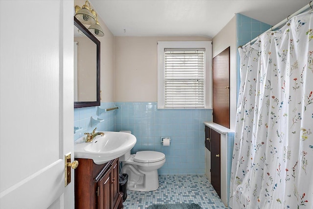 bathroom with a shower with shower curtain, tile patterned floors, vanity, tile walls, and toilet