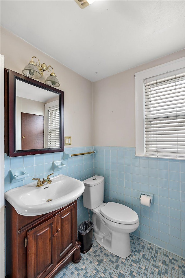 bathroom featuring toilet, vanity, tile patterned floors, and tile walls