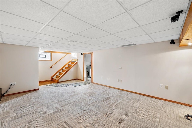 basement with a paneled ceiling and carpet floors