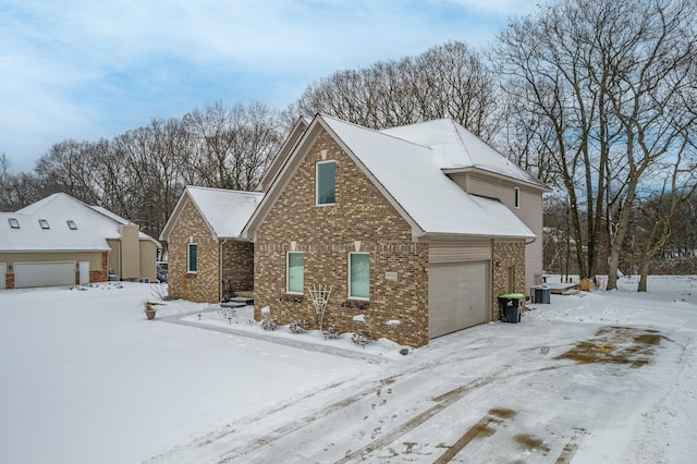 snow covered property with brick siding and central AC