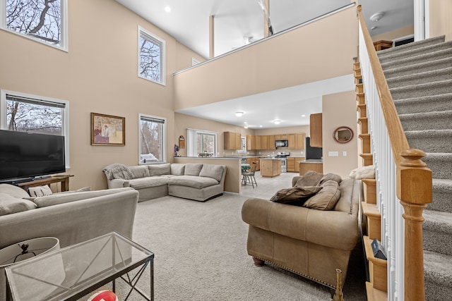 3700 Marie Meadows Dr, White Lake, MI 48383 - living area with stairway, light colored carpet, a high ceiling, and recessed lighting